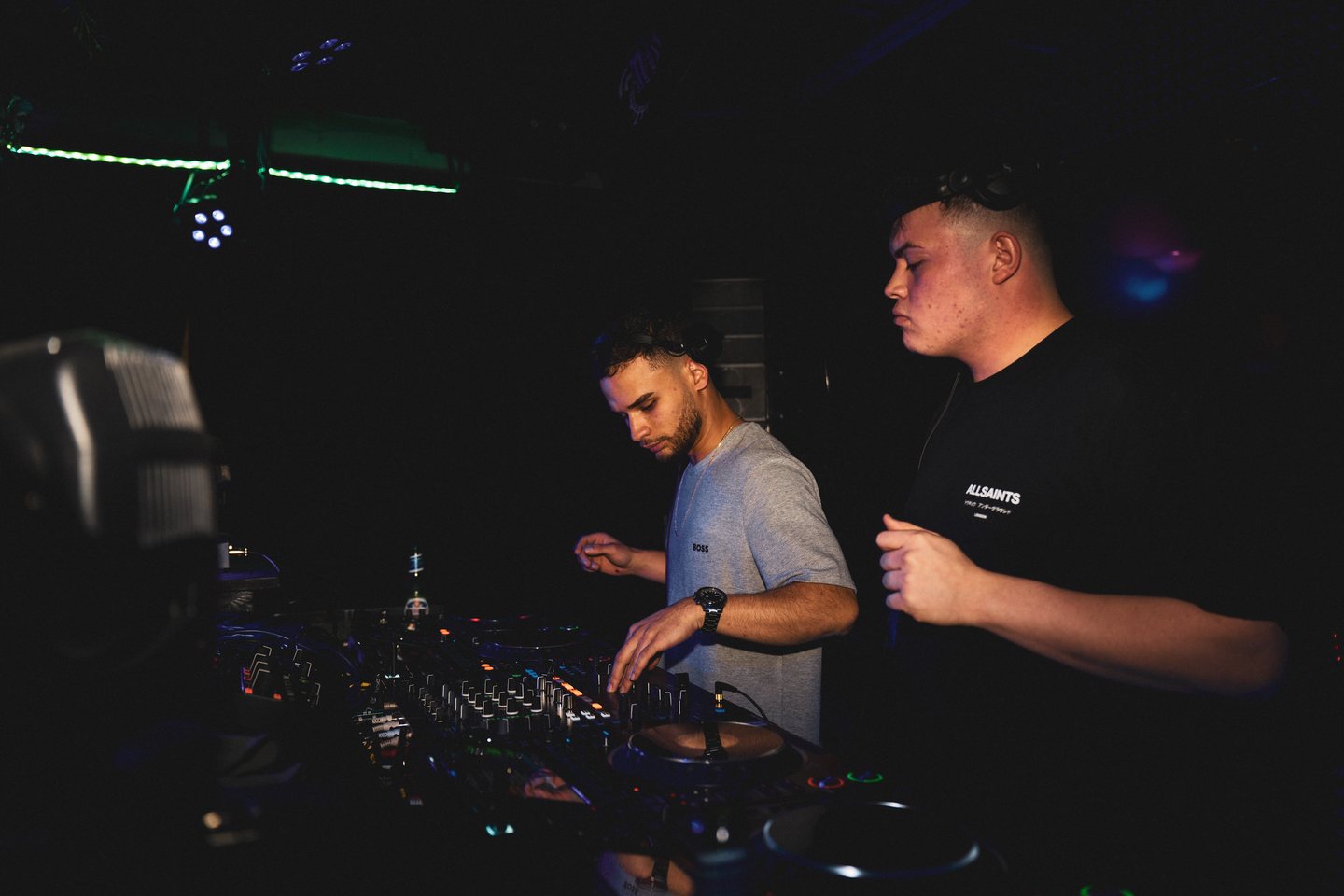 Jeremias and Arias side by side behind the CDJs during a club set.